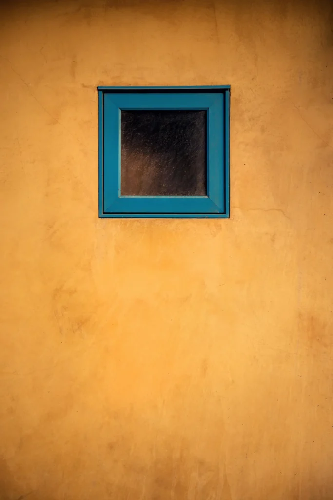 Fenêtre au cadre bleu sur un mur ocre