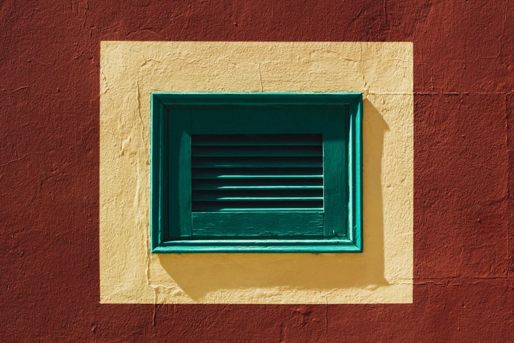 Grille verte encadrée par un mur rouge