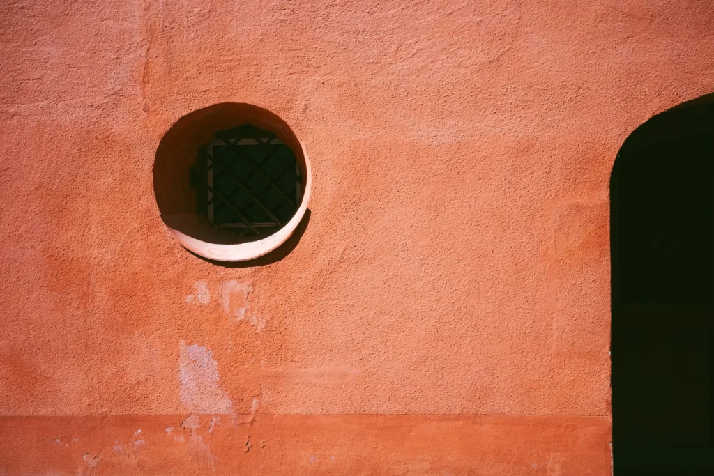 Fenêtre ronde sur un mur terracotta