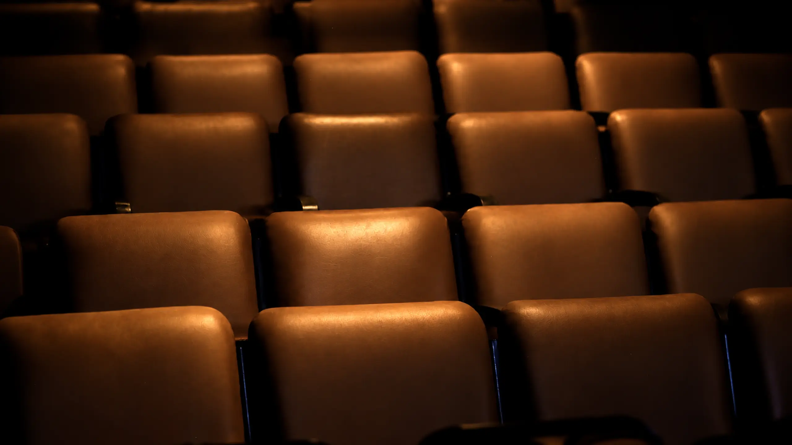 Fauteuils ambrés d’un auditorium en lumière basse