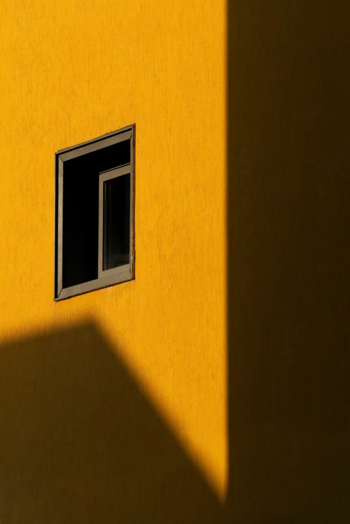 Mur jaune avec fenêtre et ombre profonde