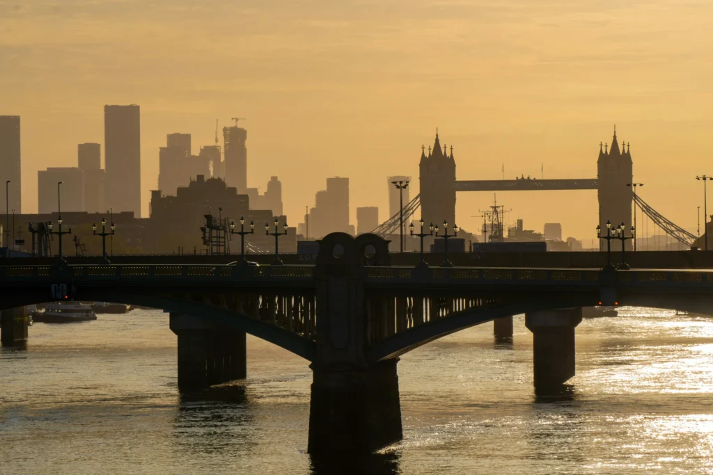 Tower Bridge et la Tamise devant la silhouette de Londres au soleil couchant.